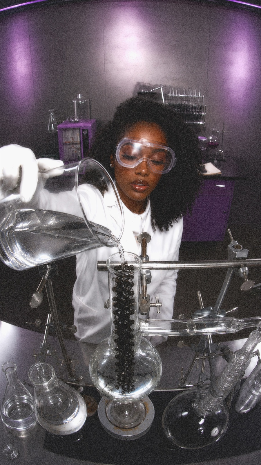 A woman in safety goggles conducting an experiment with laboratory glassware